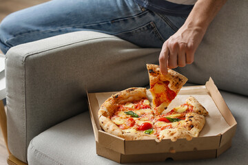 Young man eating tasty pizza at home
