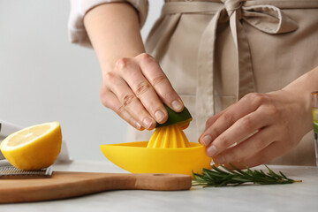 Woman squeezing lime on table in kitchen