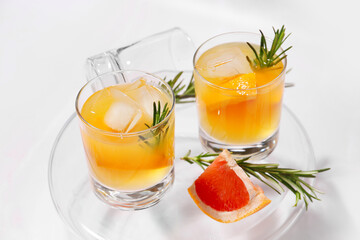 Glasses of tasty grapefruit cocktail with rosemary on white background