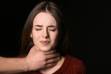 Man holding young woman by throat on dark background. Concept of harassment - obrazy, fototapety, plakaty