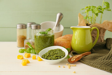 Bowl with tasty pesto sauce, cheese and pine nuts on light wooden table