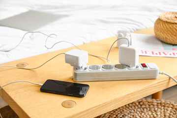 Extension cord with charging gadgets on table in bedroom