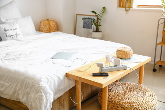 Extension Cord With Charging Gadgets On Table In Bedroom