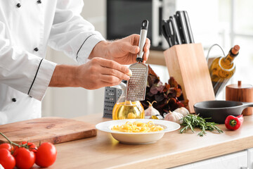 Italian chef grating garlic into pasta in kitchen, closeup