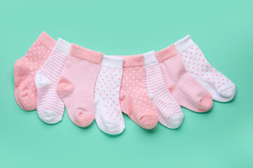 Different baby socks on color background