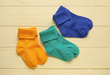 Baby socks on color wooden background