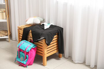 Stylish school uniform with backpack in room