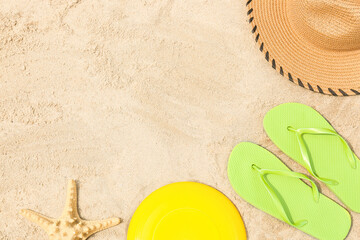 Fototapeta na wymiar Frisbee disk, hat, flip-flops and starfish on sand