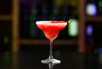 Glass of tasty strawberry margarita  on table in bar