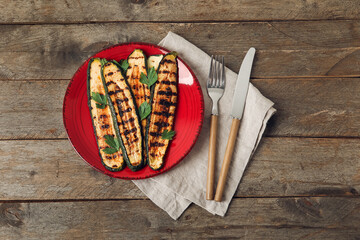 Plate with tasty grilled zucchini on wooden background