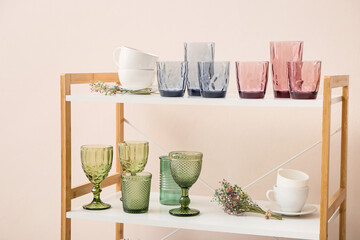 Empty stylish glasses on shelf unit near color wall