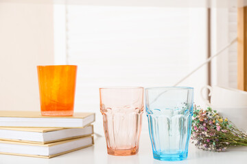 Empty stylish glasses and books on table in room