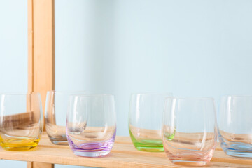 Empty stylish glasses on shelf unit near color wall