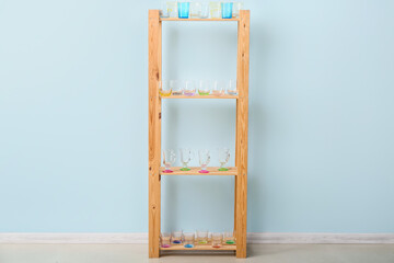 Empty stylish glasses on shelf unit near color wall