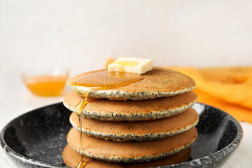Bowl of tasty pancakes with honey and butter on light background