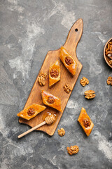 Wooden board with tasty baklava on grunge background