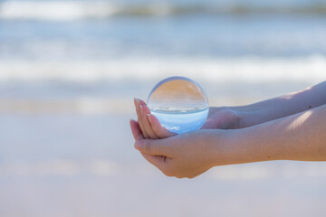 夏の海の海岸で両手を水晶ガラスボールを持っている女性の姿