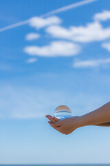 Fototapeta na wymiar 夏の海の海岸で両手を水晶ガラスボールを持っている女性の姿