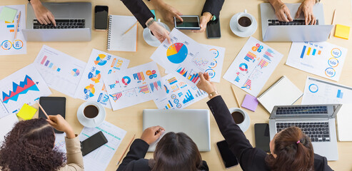 Table top view of a wooden conference table with different charts and graphs papers on it and six...