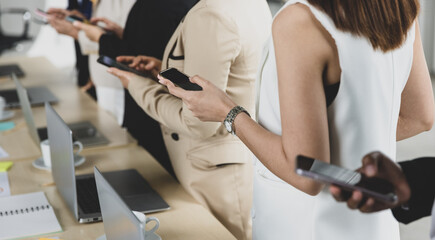 Selective focus on five Asian business women in formal suits torso standing together in office using smartphones