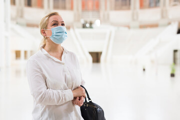 Portrait of attentive senior woman in protective face mask visiting museum