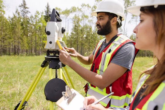 Surveyors using equipment to measure field