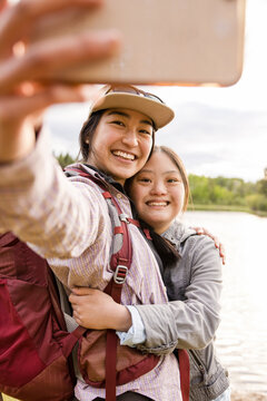 Sisters taking selfie on lake shore
