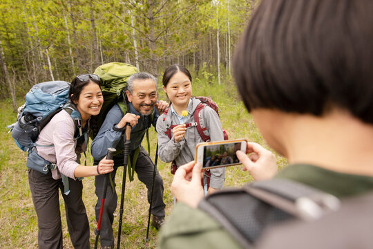 Woman taking photo of family walking in forest