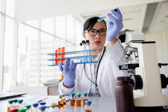Female scientist examining liquid vial in laboratory