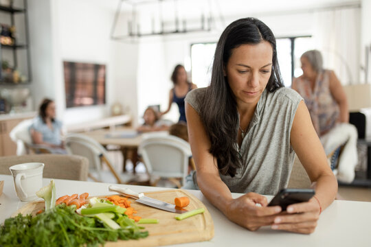 Woman with smart phone taking a break from cooking in kitchen