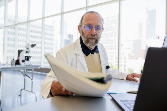 Senior Male Scientist Reviewing Research Notes At Desk In Laboratory