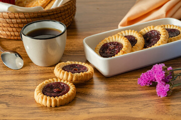 strawberry jam tarts and a cup of coffe, wood table, breakfast time