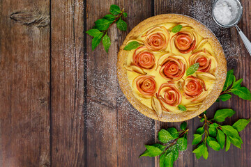 Fototapeta na wymiar Apple shaped like roses on tart on rustic wooden table.