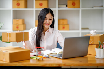 Fototapeta na wymiar Starting Small business entrepreneur SME freelance,Portrait young woman working at home office, BOX,smartphone,laptop, online, marketing, packaging, delivery, b2b,SME, e-commerce concept
