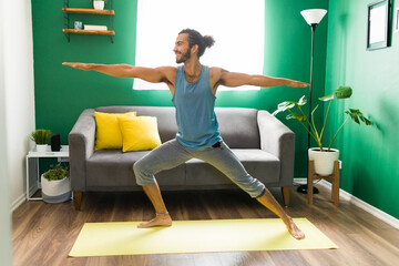 Naklejka premium Hispanic man smiling while doing yoga
