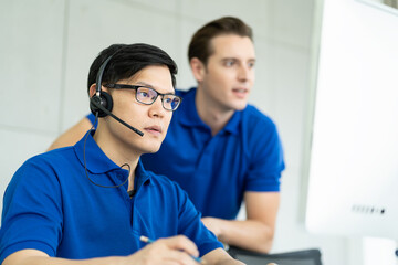 Young handsome man with headset working in call center, Technical support operator with team as customer service in the office