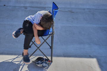 bored and tired latino kid alone lying on a chair covering his face. devastated and resting. horizontal