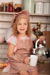 a small curly American girl pours liquid from a kettle at home in a cup against the background of the kitchen with a place for text