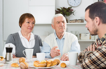 Aged grandfather teaches and instructs his grandson at table at home