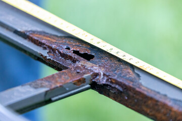 measuring corroded metal frame with rusty hole