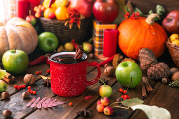 red mug with mulled wine. Cinnamon sticks stick out of the cup and a star of star anise floats....