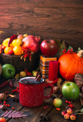 Obraz na płótnie Canvas red mug with mulled wine. smoke comes from the mug. Cinnamon sticks stick out of the cup and a star of star anise floats. Fruits and spices are all around on a wooden table