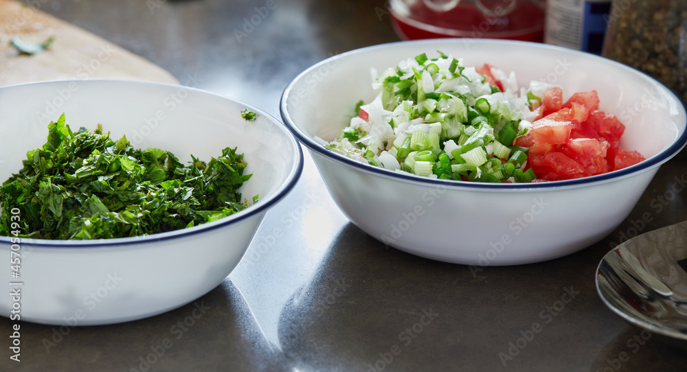 Wall mural Prepared ingredients basil, green onions and tomatoes, chopped in salad bowls