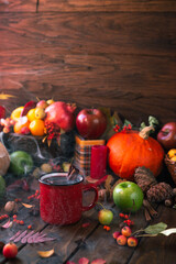 red mug with mulled wine. smoke comes from the mug. Cinnamon sticks stick out of the cup and a star of star anise floats. Fruits and spices are all around on a wooden table