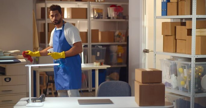 Male hacker in janitor uniform steal information on laptop in modern warehouse