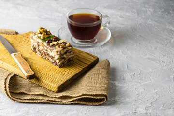 a piece of homemade sesame tahini halva on a wooden board close - up next to a knife and a cup of tea