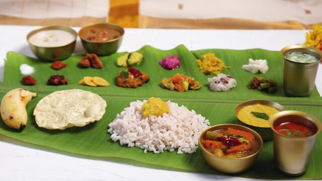 Woman hand serving  parippu dal curry ghee traditional Onam sadhya 4K footage video rice Sambar, Rasam,  Avial,  Pappadom Payasam on banana leaf Onam Vishu festival vegetarian food Kerala South India.