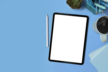 Top view digital tablet, stylus pen and supplies on blue background.