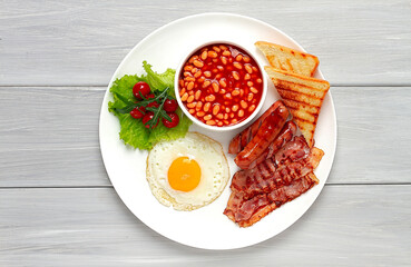 Traditional Full English breakfast, on a white background, fried eggs with fried bacon, sausages, white beans ,cherry tomatoes, horizontal, no people,