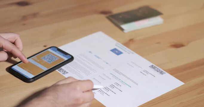 Vaccinated person checking digital health passport app in mobile phone with covid-19 vaccination certificate for safe travel